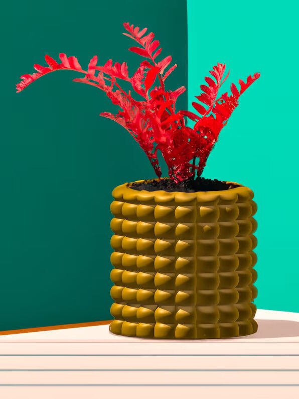 Yellow Corn Cob planter from Rosebud Home Goods with a red plant in it and a green background behind.