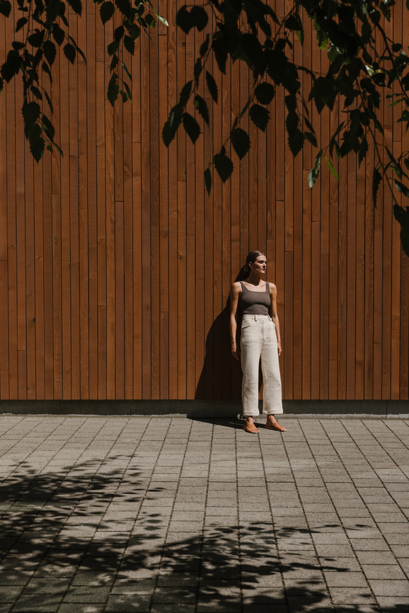 fashionable woman posing in front of modern architecture on bright sunny day