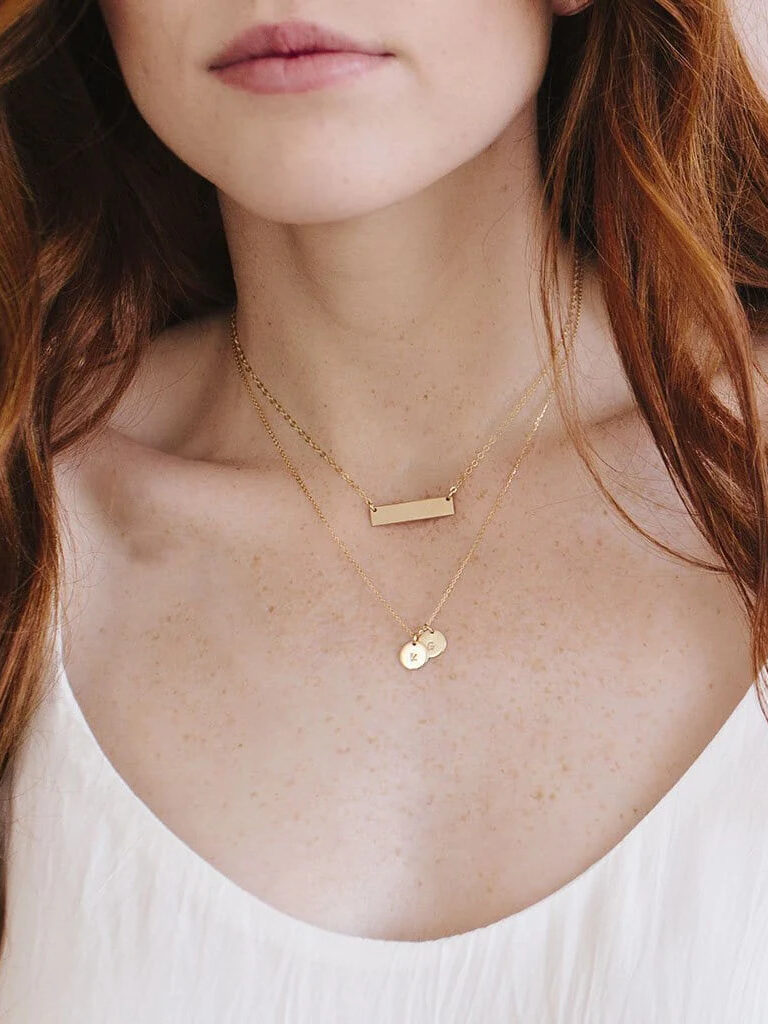 A close up shot of a model wearing two gold pendant necklaces by Made by Mary.
