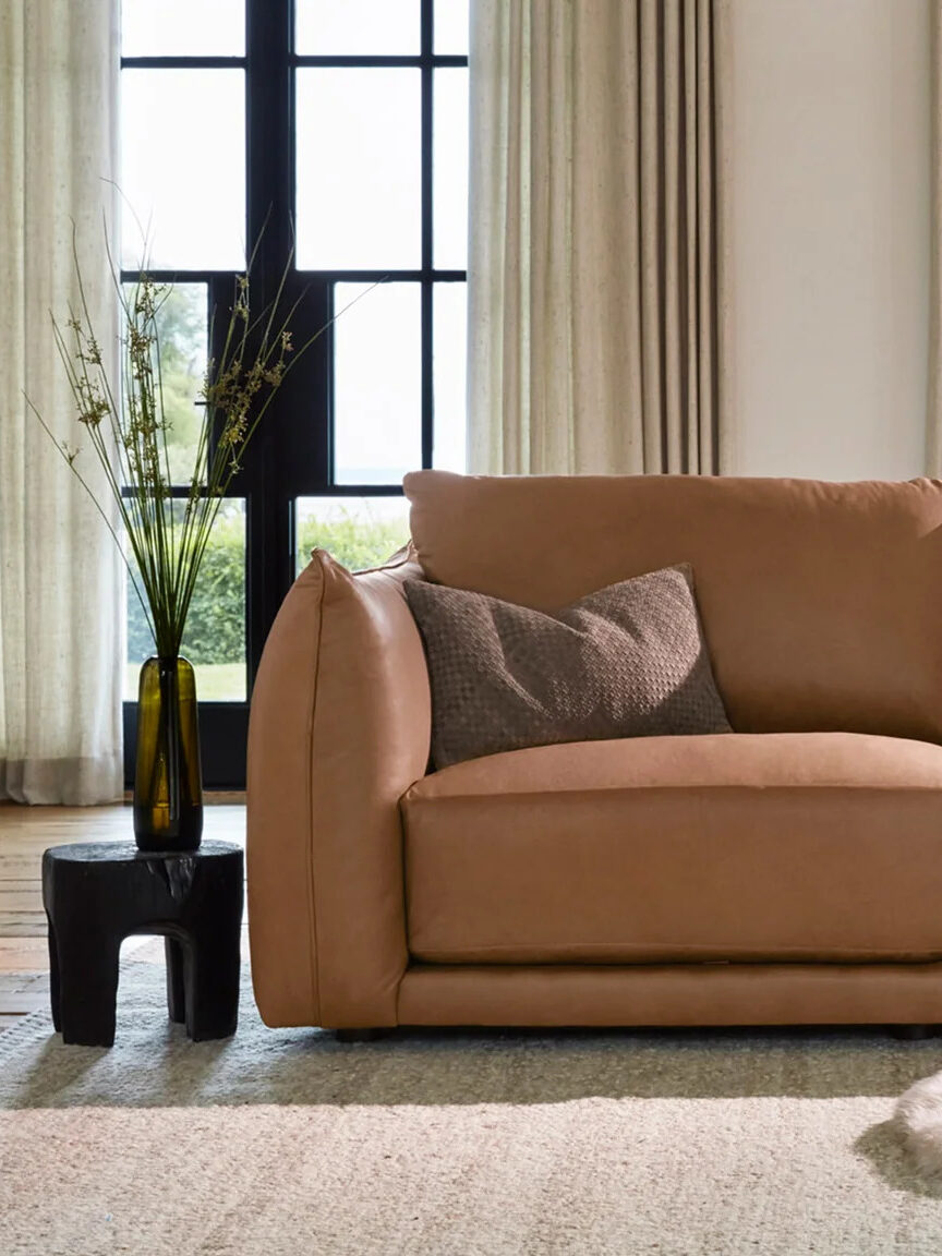 A Maiden Home camel color sofa in a living room.
