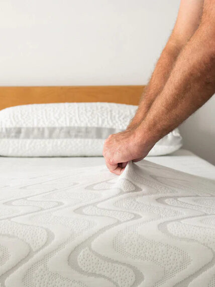 A pair of hands pulling up on the top cover of a Nest Bedding Mattress.