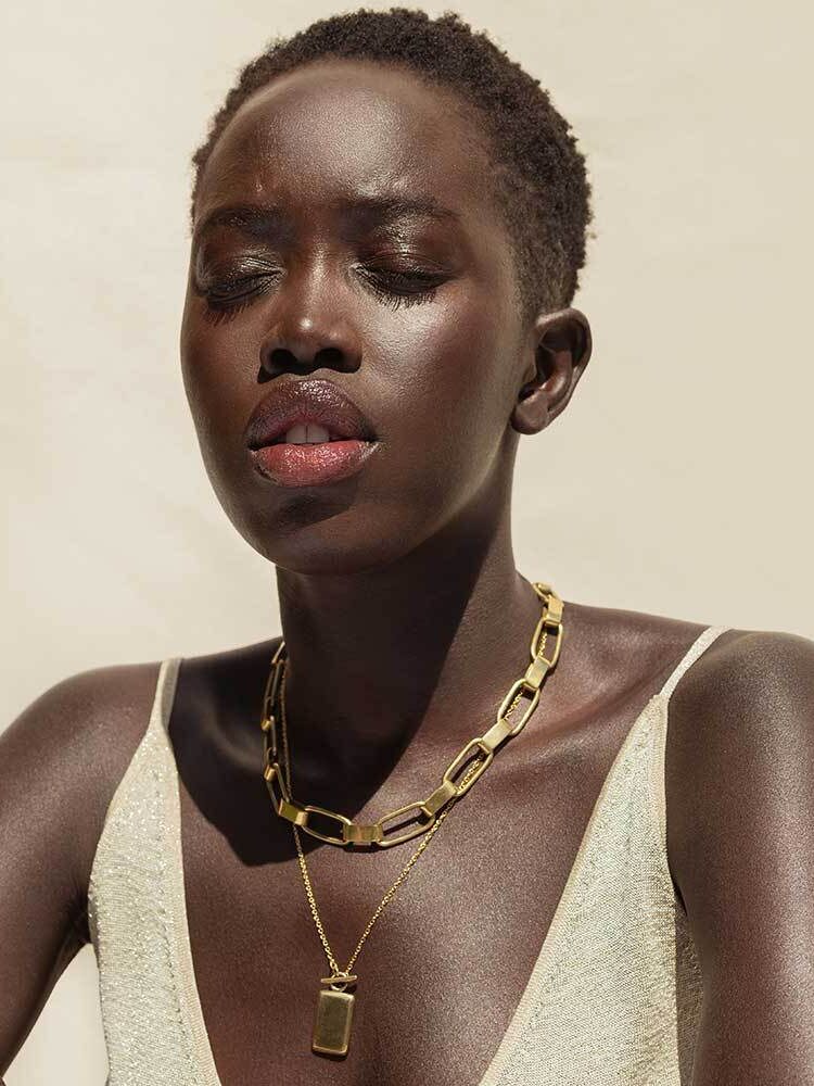 A model wearing two gold statement necklaces by SOKO.